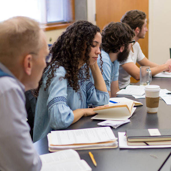 Students in a classroom round table discuss a book