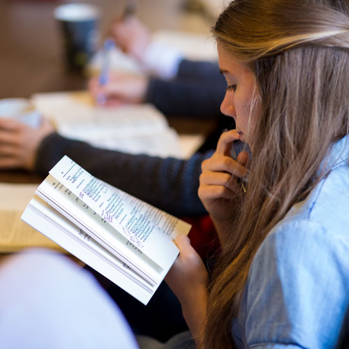 student sitting in seminar reading a book