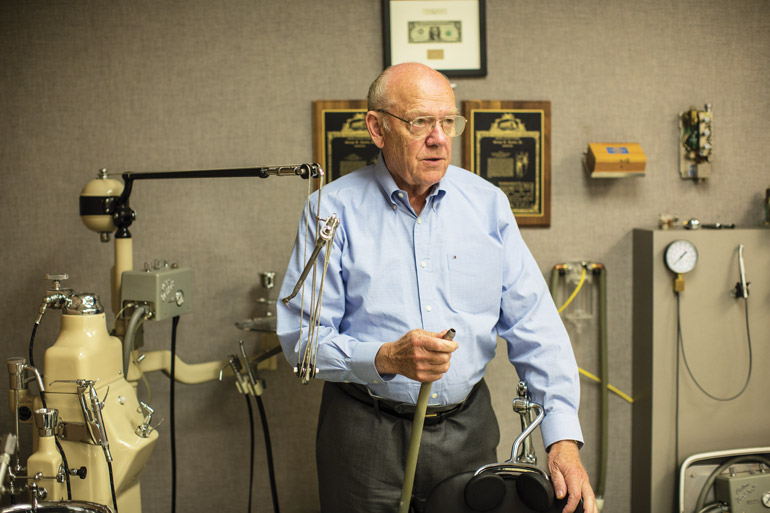 Ken Austin holds up an early version of his dental vacuum system that first put A-dec on the map.