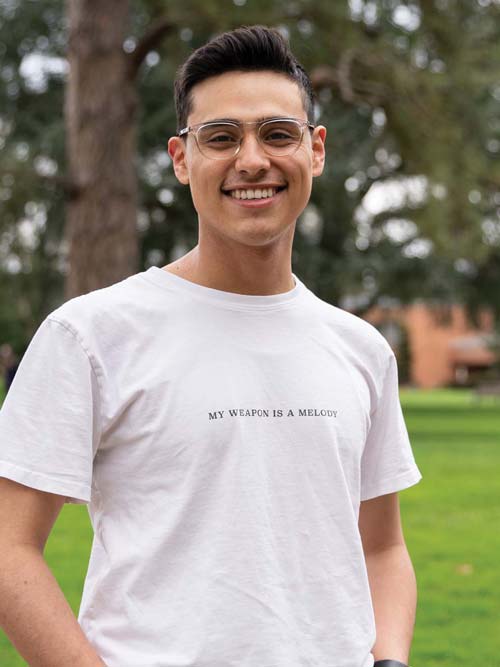 Student Saturn Macias standing on the campus quad looking at the camera