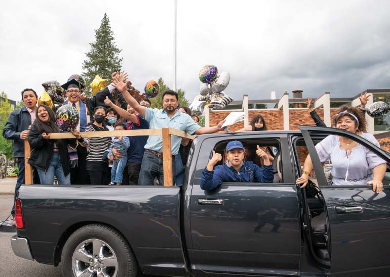 A student and his family in the back of a pickup truck with baloons on it