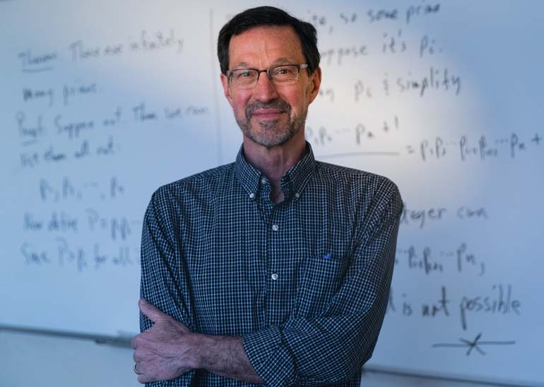 John Johnson standing in front of a whiteboard with math equations on it