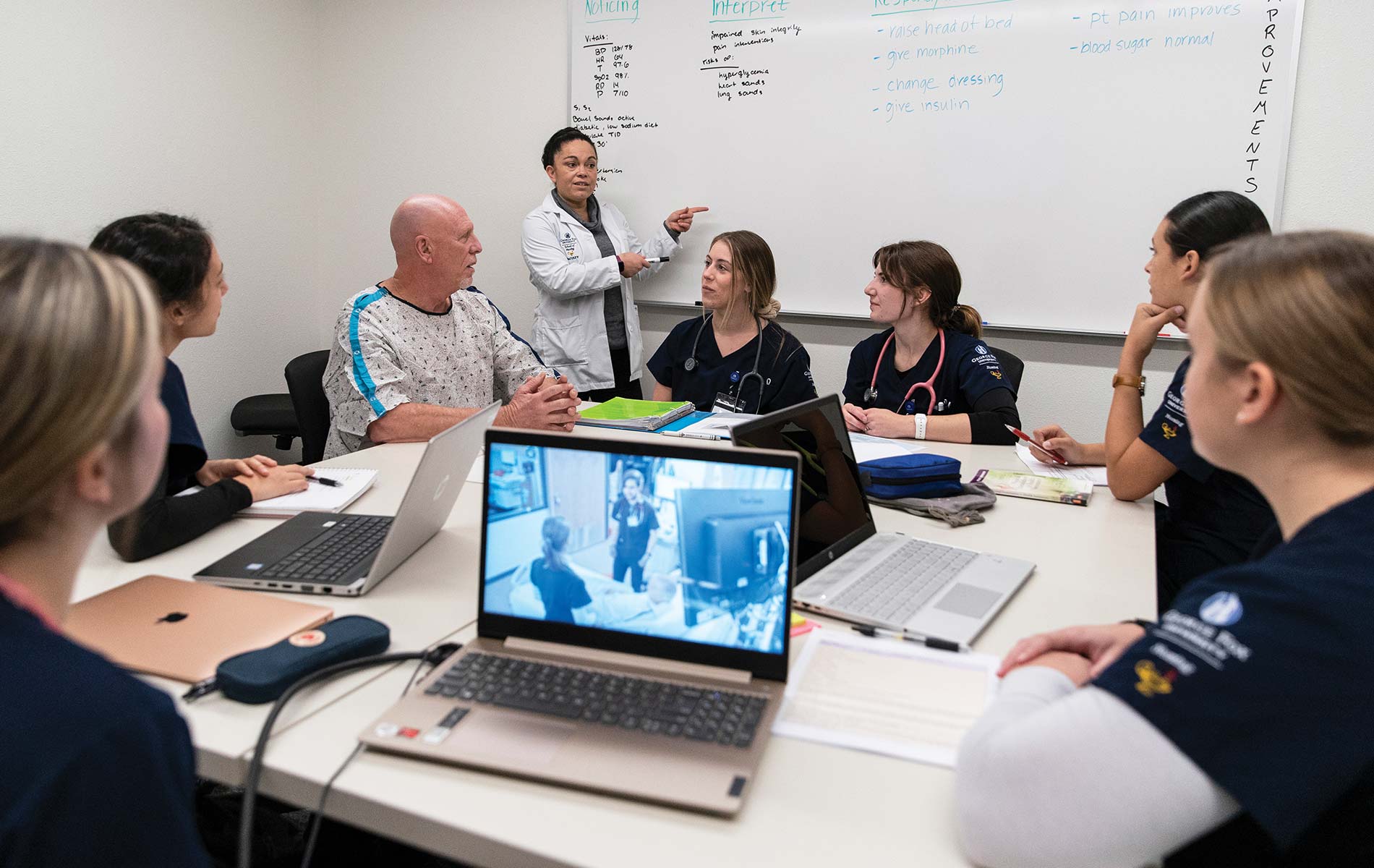 Nursing students debrief with a professor and the “patient” after a simulation. 