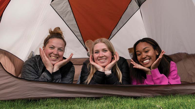 Three female students in a tent