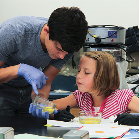 A biology student and a child sharing their science experiment