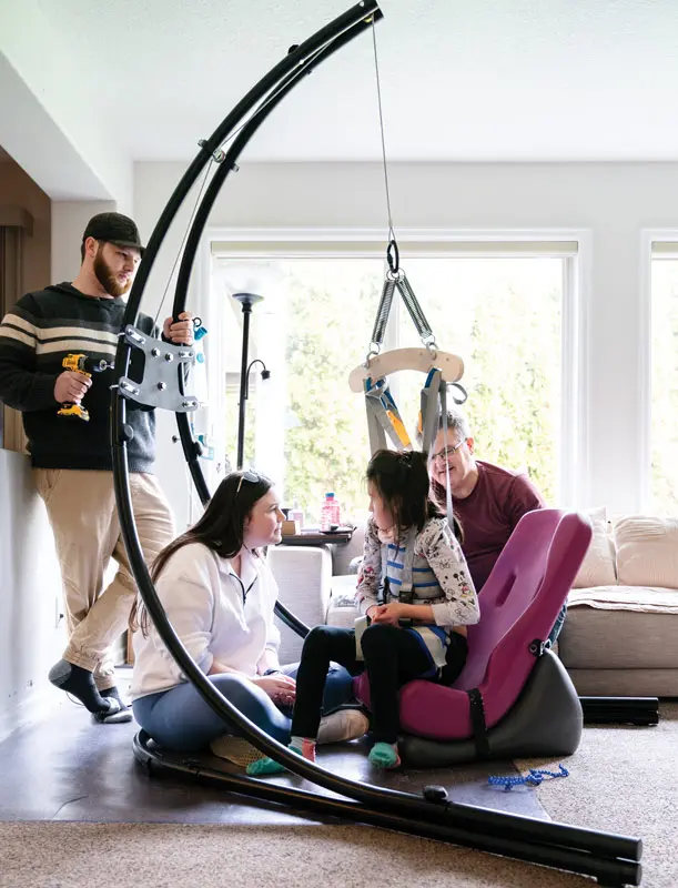 Genevieve tries out a prototype of the Bouncinator 3000 that uses a harness, while her dad Fred and biomedical engineering major Maddie Carniglia look on.