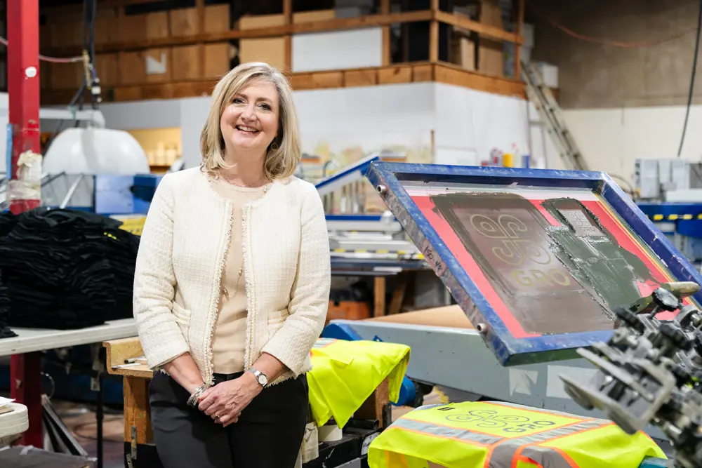 Aly Salz standing in front of a screen printing machine at Righteous Clothing Agency