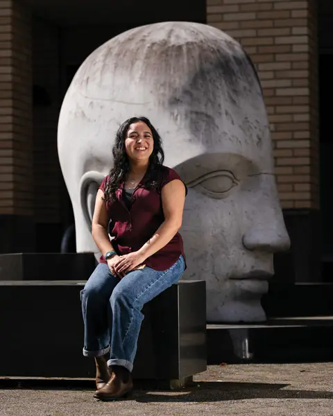 Frankie dits by a large stone carved head outside