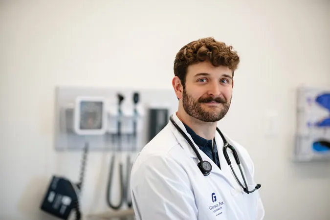 A George Fox medical student poses for a photo in scrubs in a medical room