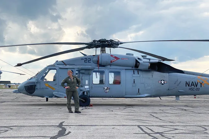 Allison Moss stands in front of a navy helicopter