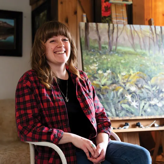 Christine sits and smiles in her studio