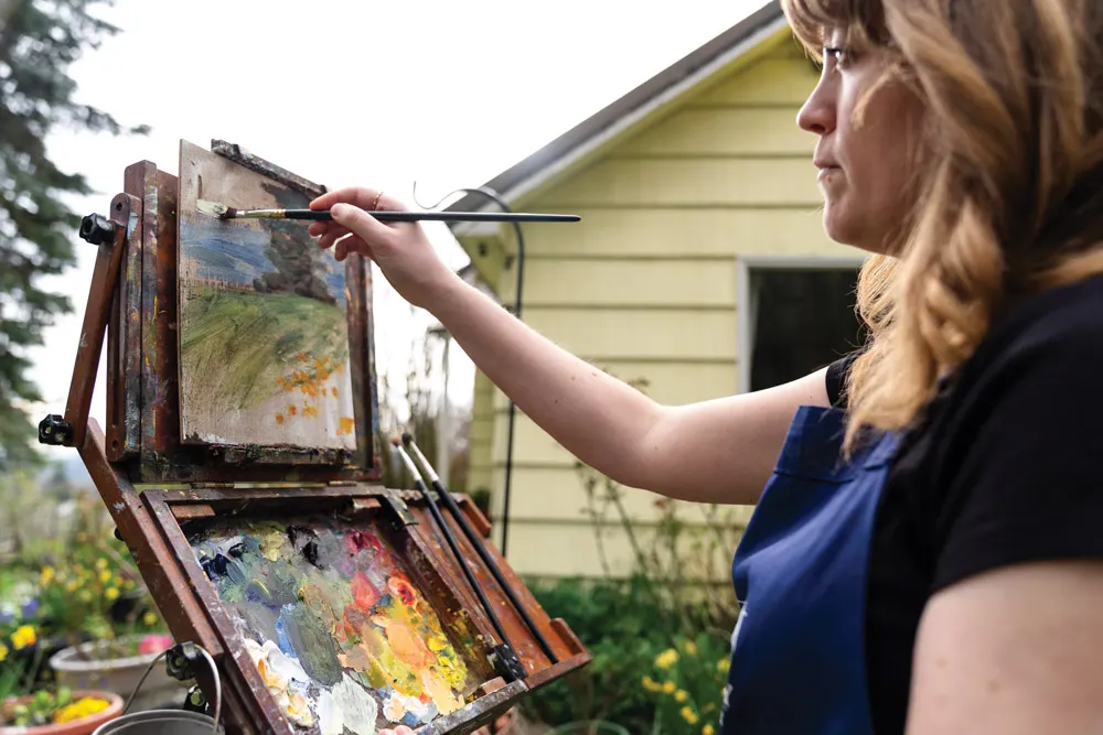 Christine Joy works outside at an easel on a painting