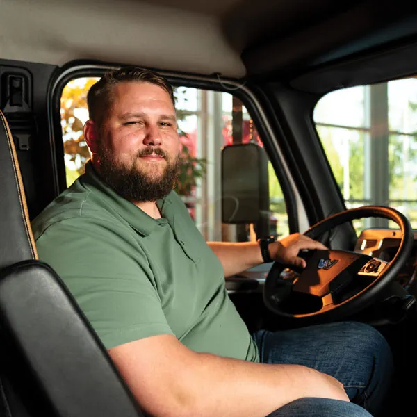 A man is sitting in a truck, driving it. 