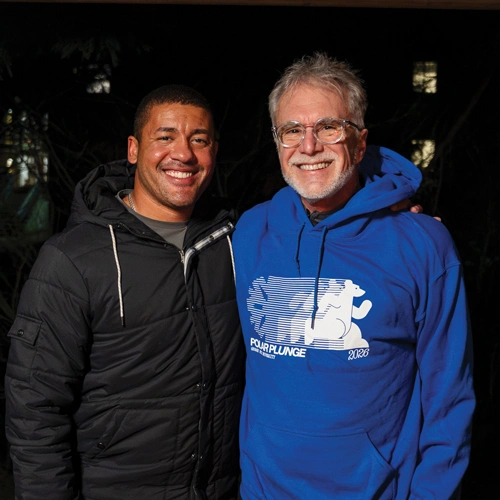 Marvin smiling for the camera with President Baker, who's wearing his freshly-earned polar plunge sweatshirt