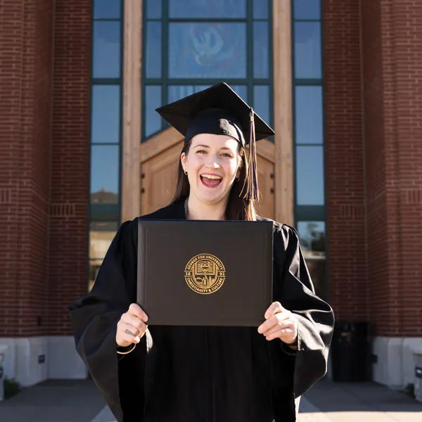 Tia holds her diploma from George Fox and smiles