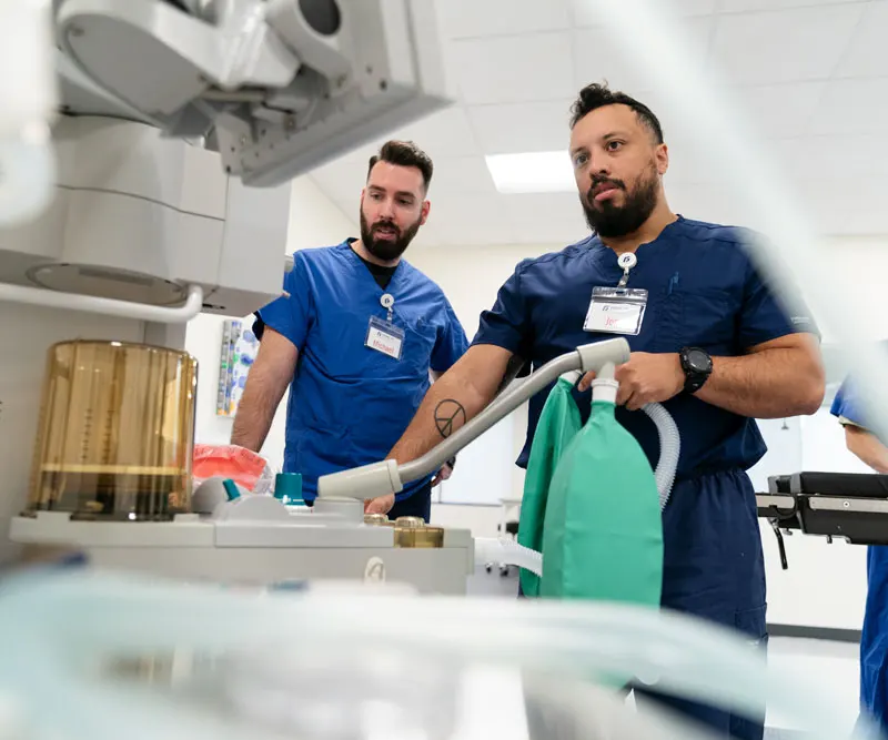 CRNA student looks at data on a machine while a nurse supervises