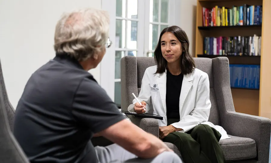 Mental health nurse talks in a white coat talks with an older patient