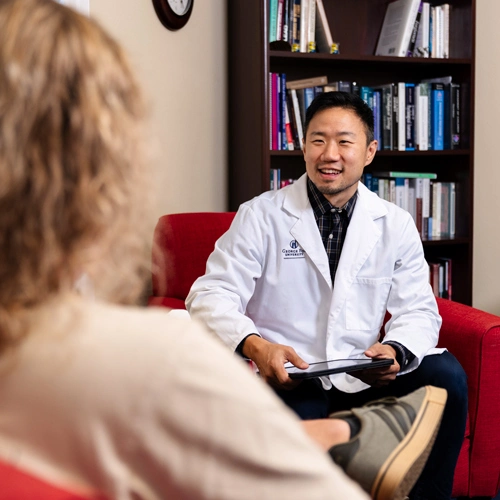 male PMHNP talking to a patient in his office