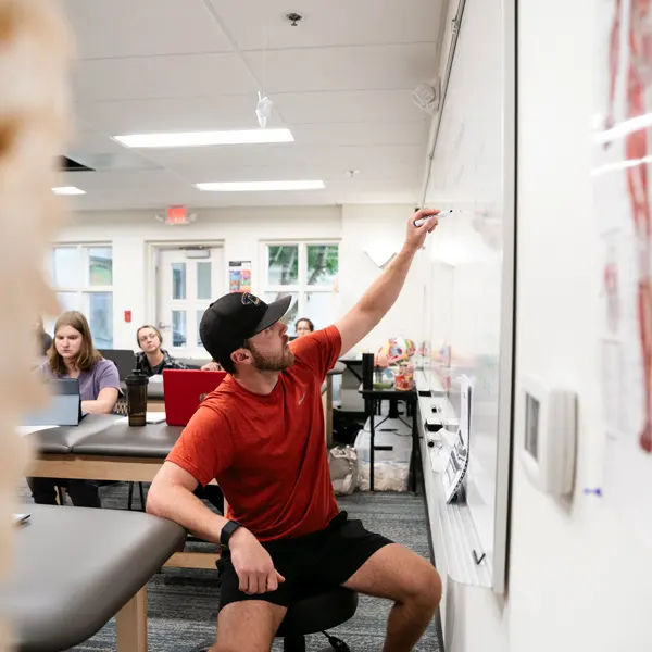 A George fox OT student writes on a whiteboard in class