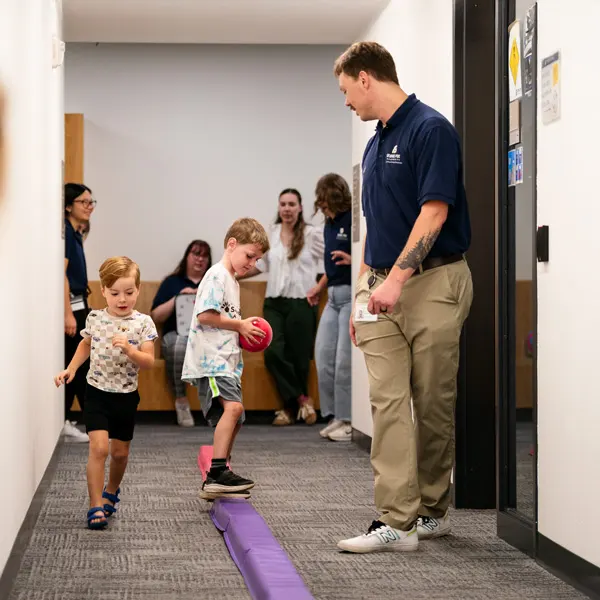 2 OTD students work at in a hallway with kids on their motor skills
