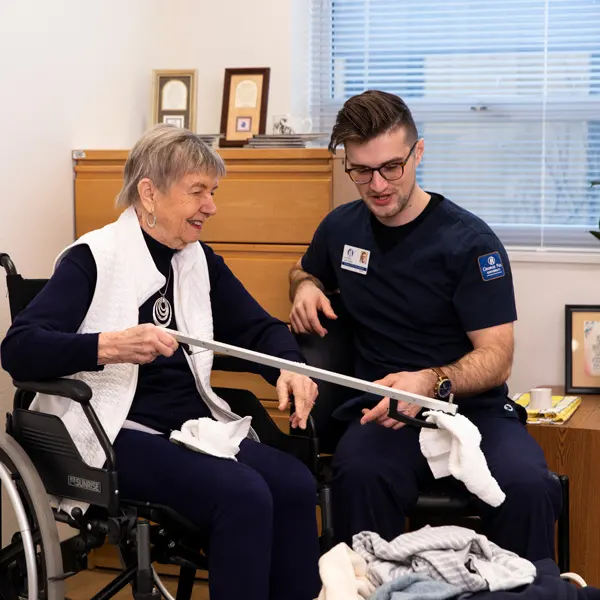 OTD student assists an older female patient in a wheelchair with her laundry
