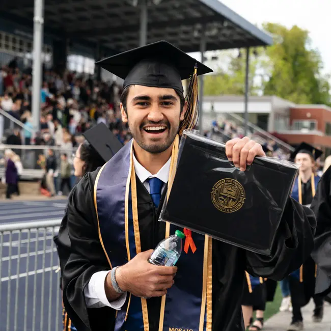 Happy graduate cheers and shows his diploma