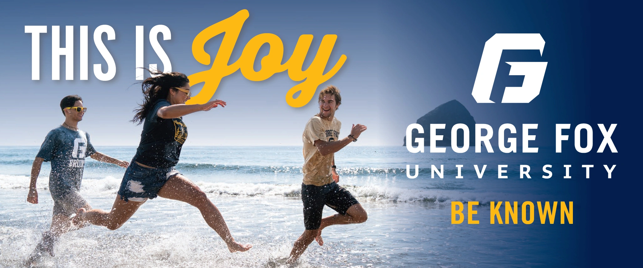George Fox billboard of students running on the oceanside with 'This is Joy" in large text