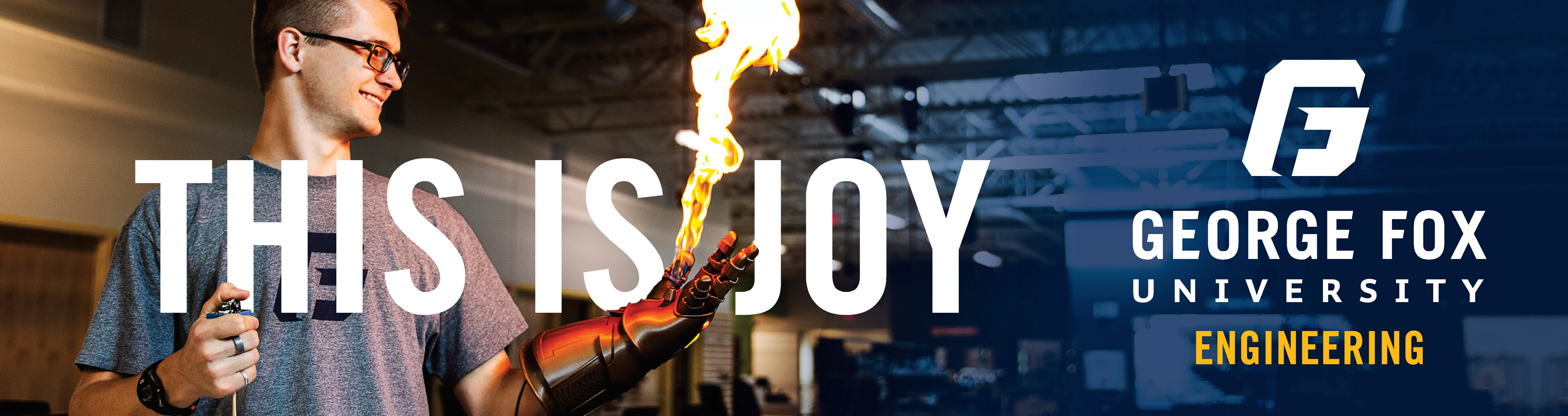 billboard of a smiling engineering student wearing a glove with fire coming out of his palm, with 'this is joy' in large text