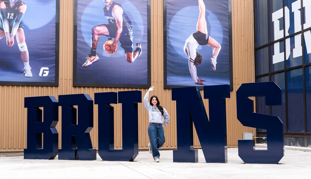 student standing as the letter 'I' in 'BRUINS' lettering installment