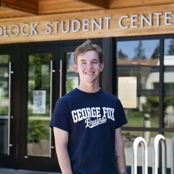 Student wearing a George Fox T-shirt standing in front of Hadlock
