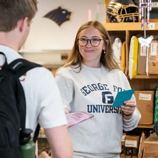 Student handing mail to another student in the mail room