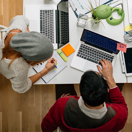 Two people using laptops for finding resources