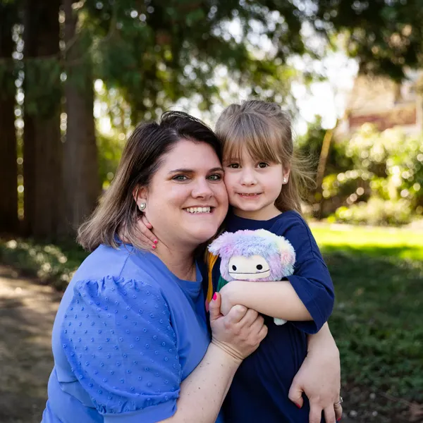 Employee poses with her 4 year old daughter on campus