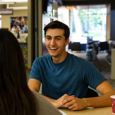 Student and employee talking at a table