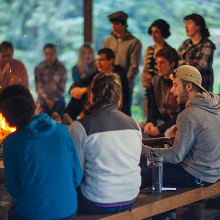 Students gather around the fire for a small group faith sharing