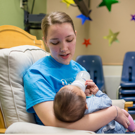 Volunteer for Fostern Parent Night Out holding a baby.