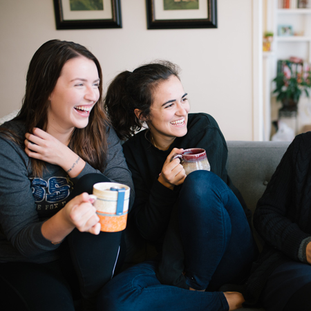 Two students laugh on a couch