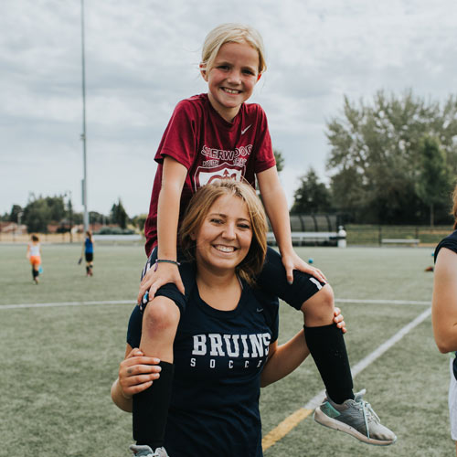 kid sits on college student's shoulders