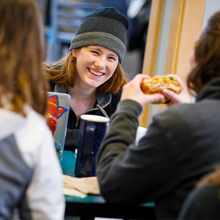 Three students laughing together in the dining hall