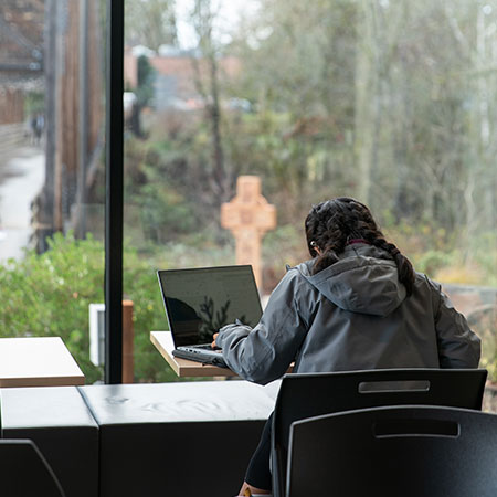 A student studying in the Canyon Commons while it's raining outside