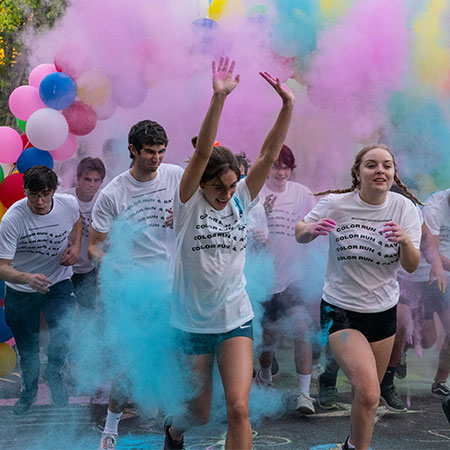 Students run through clouds of color 