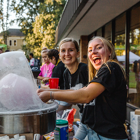 Student volunteers working with the cotton candy machine for an event