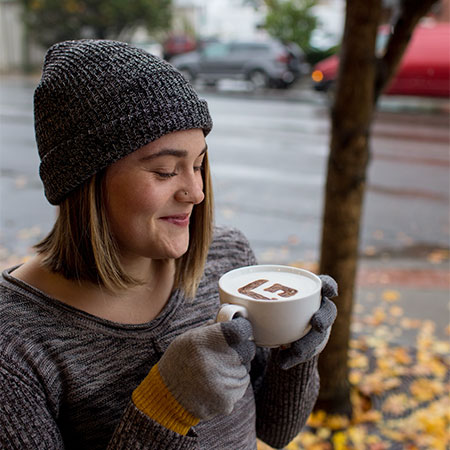 A student smiling with a cup of latte