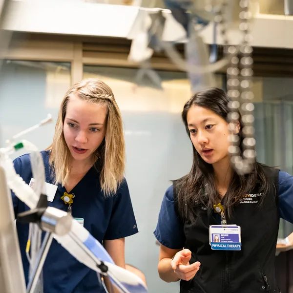 A George Fox student works a clinical rotation at Providence, with a Physical Therapist giving pointers