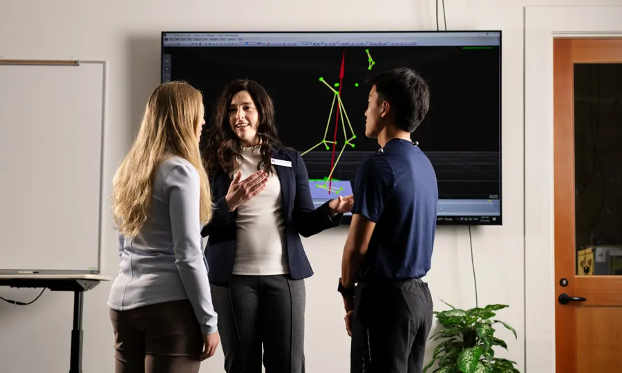 Two students stop to talk with a DPT professor in the simulation room