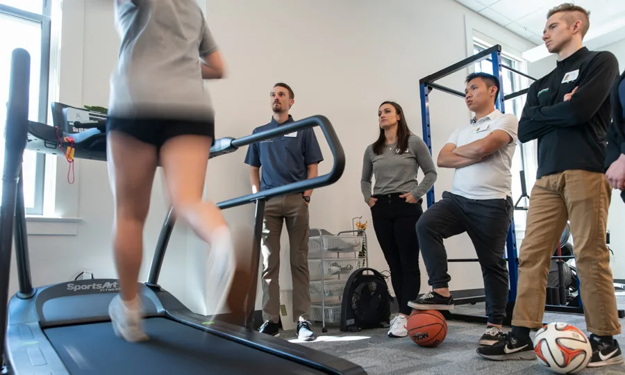 Four Physical Therapy students watch a runner on a treadmil