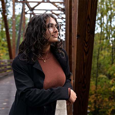 A pensive graduate student pausing on the bridge on campus