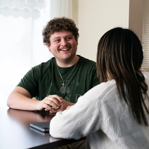 student sitting at a table talking to their mentor
