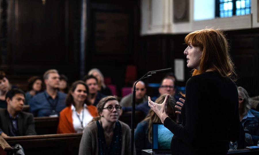 A woman speaks in front of an audience