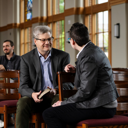 Student talks with a pastor in the chapel